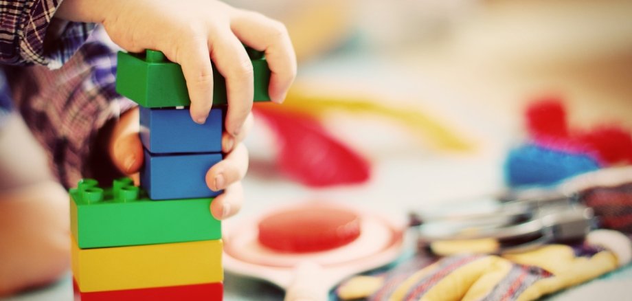 Kindhände, die aus Lego-Duplo-Steinen einen Turm bauen