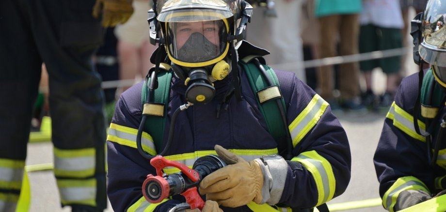 Feuerwehrmann mit Atemschutzmaske blickt in die Kamera
