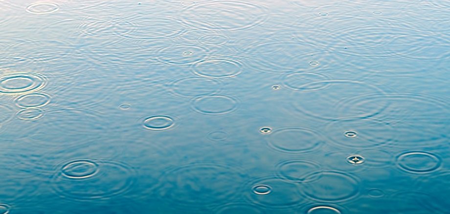 Regentropfen auf Wasser