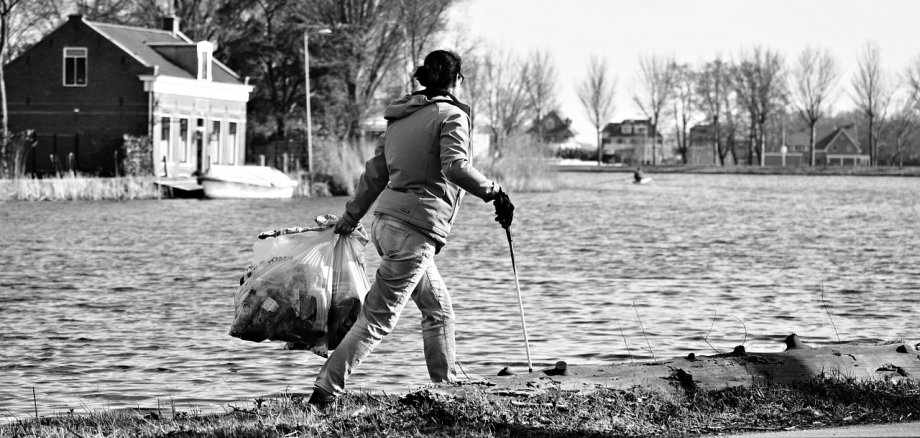 Person sammelt an Straßenrand Müll